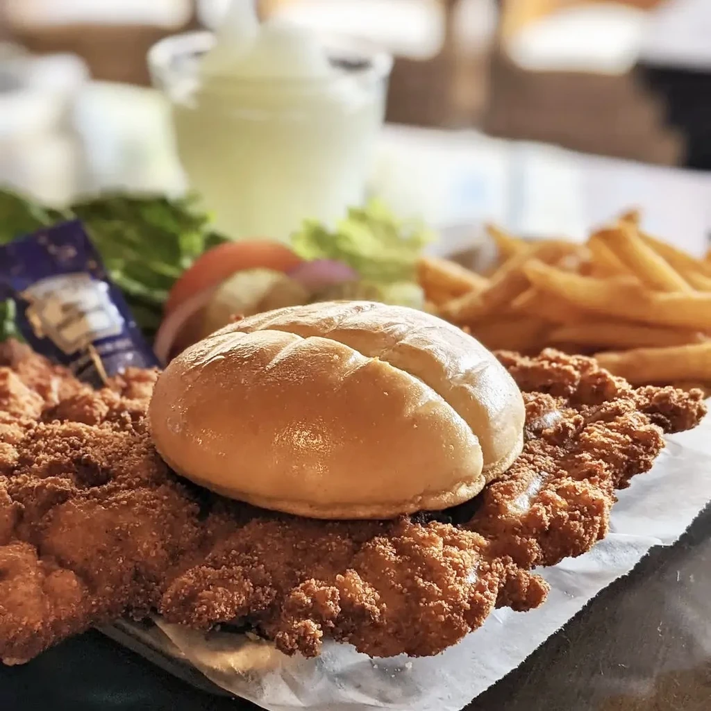 Large fried cutlet sandwich, golden fries, lettuce, tomato, and onion.