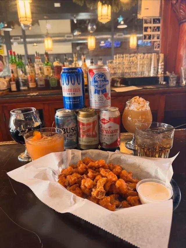 Popcorn chicken, various beers, and cocktails displayed on a bar counter.