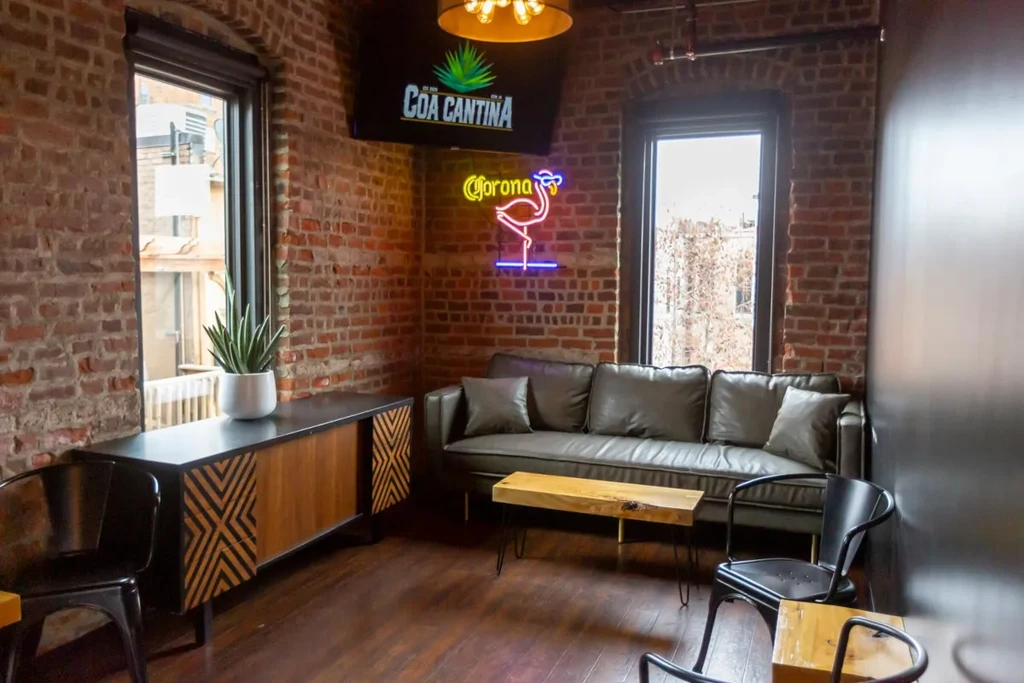 Stylish restaurant lounge with brick walls, grey sofa, and neon flamingo sign.