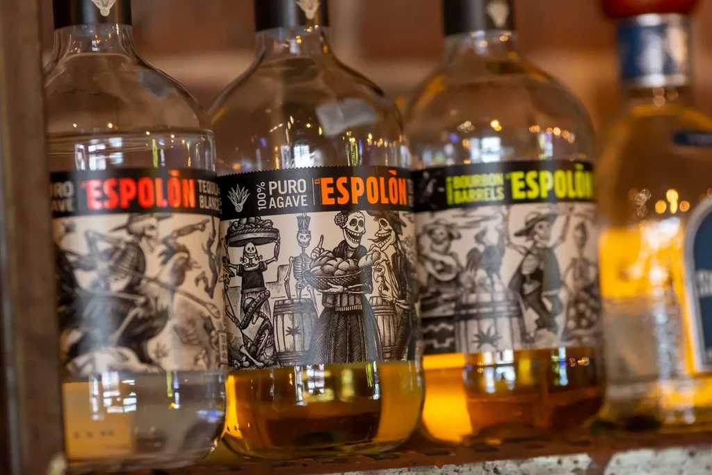 Three Espolón tequila bottles: two amber, one clear, with calavera labels.
