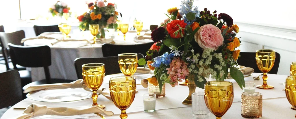 Elegant dining table set with gold-rimmed plates and a vibrant floral centerpiece.