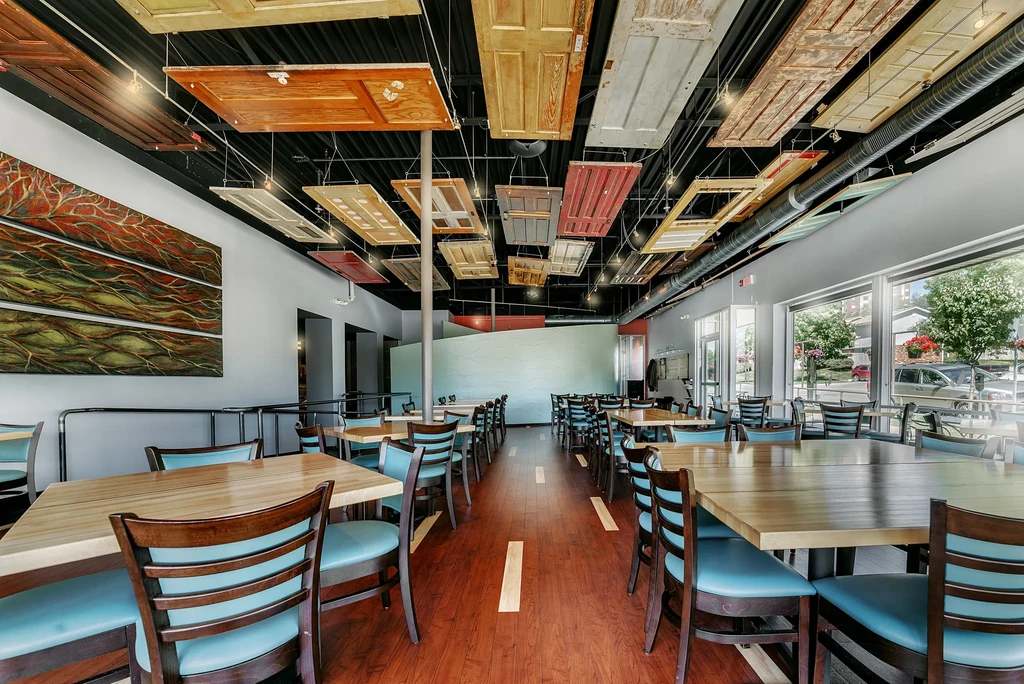 Modern restaurant interior featuring a ceiling of reclaimed doors.