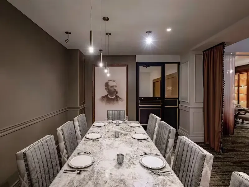 Formal dining room featuring a long set marble table and a framed portrait.