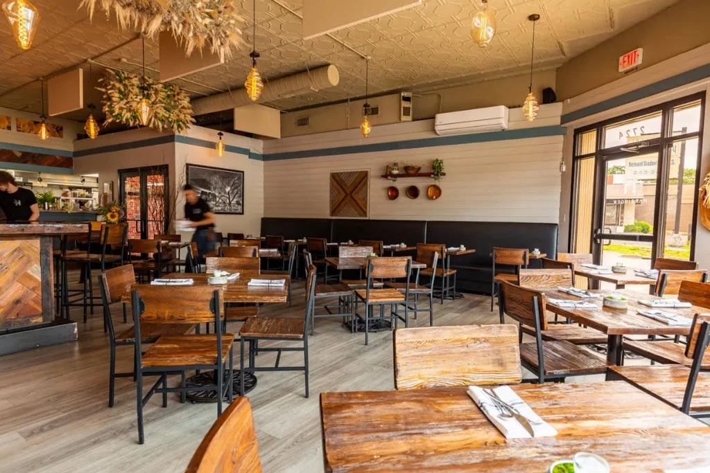 Spacious contemporary restaurant dining area with rustic-modern decor and two people.