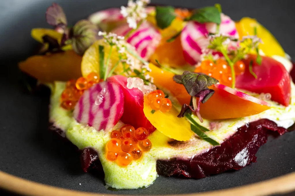 Meticulously plated colorful beets, orange roe, and green foam.