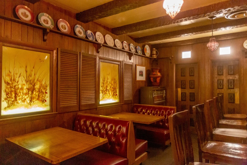 Cozy restaurant interior with red leather booths, wood panels, warm lighting.