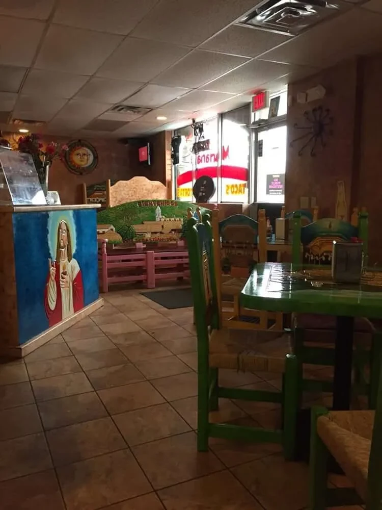 Vibrant restaurant interior featuring a colorful Jesus painting and green furniture.
