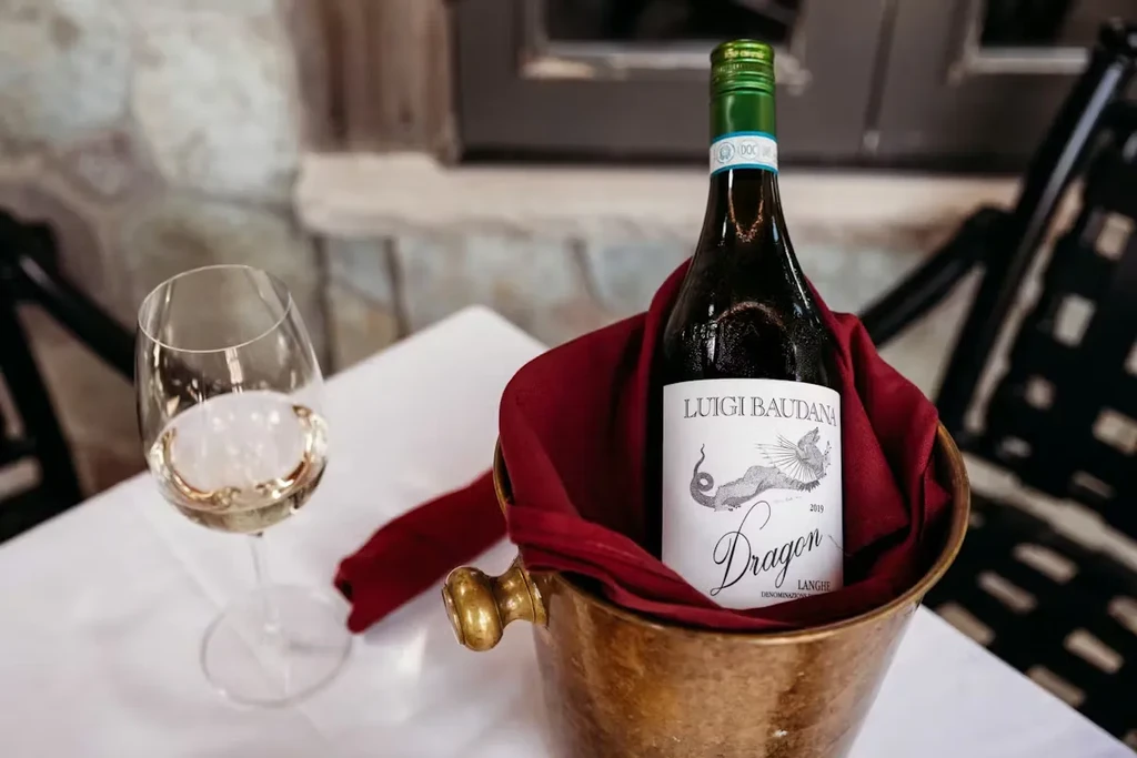 "Dragon" white wine bottle and glass chilling in a copper ice bucket.