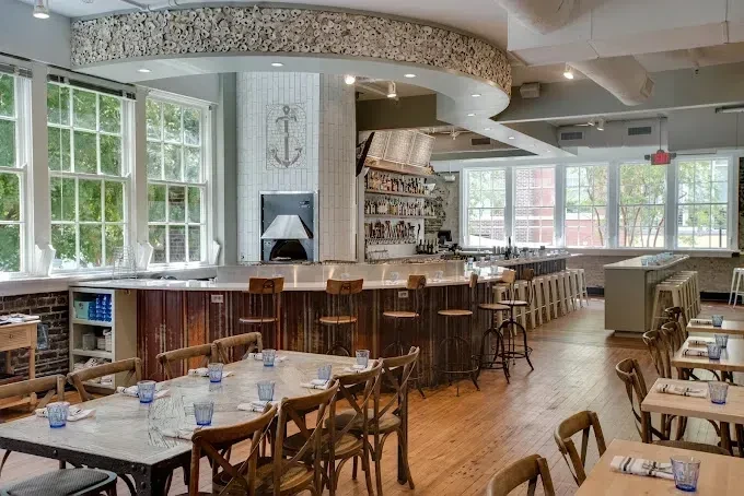 Bright, empty restaurant interior with dining tables and a large bar.