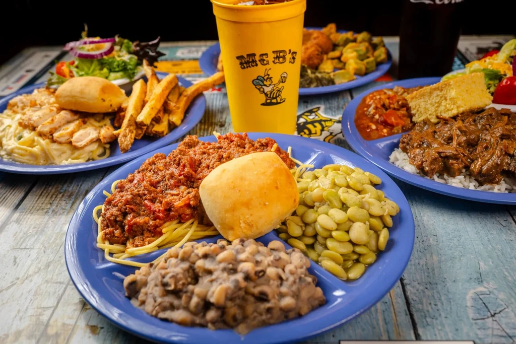 Multiple plates of comfort food meals, including pasta, stew, and salads.