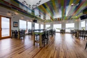 Waterfront restaurant with multi-colored striped ceiling and fish silhouettes.
