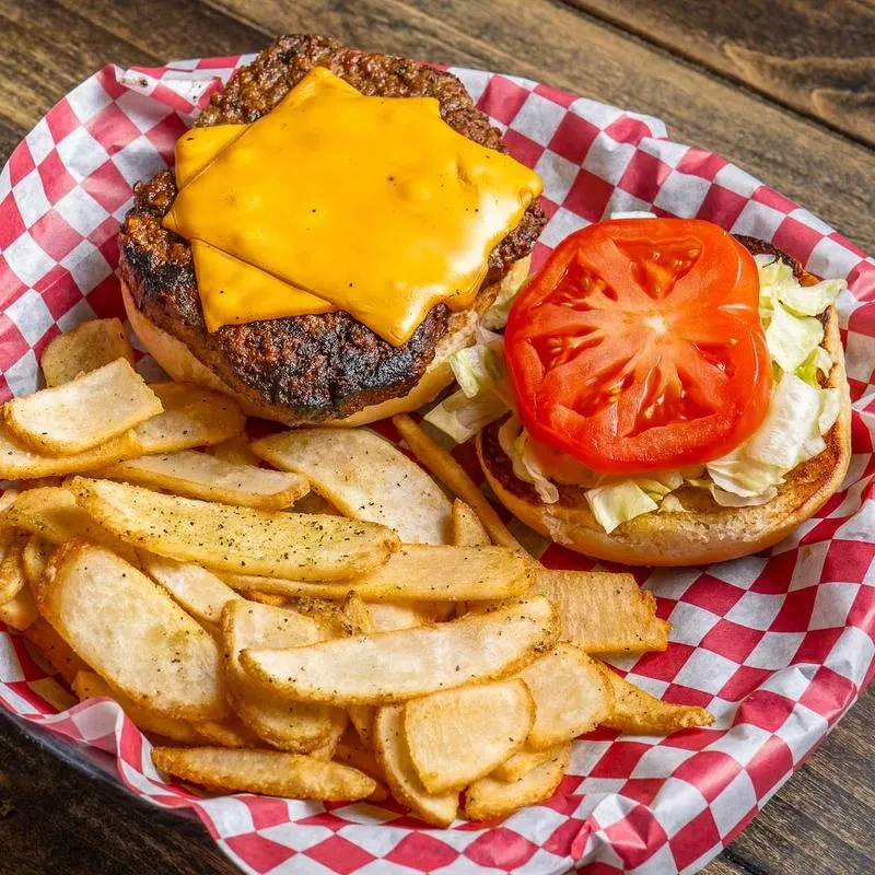 Classic open-faced cheeseburger and wedge fries in a diner basket.
