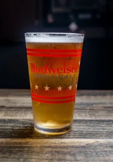 Cold Budweiser beer in a glass with American flag design.