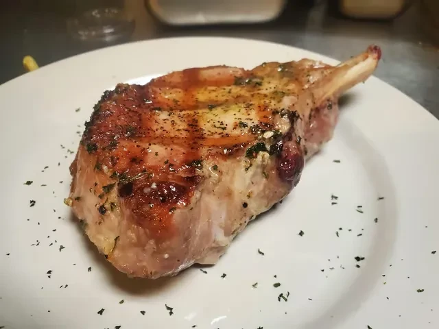 A golden-brown, seasoned bone-in chop on a white plate.