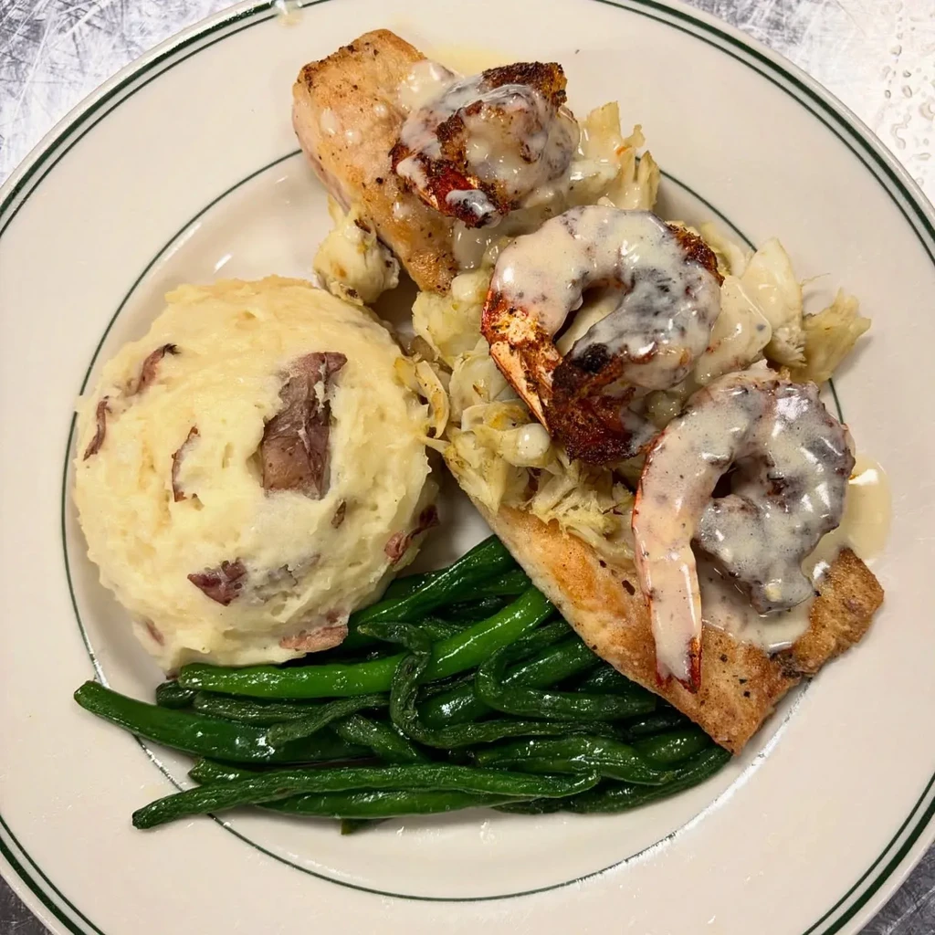 Overhead view of fish, shrimp, mashed potatoes, and green beans.
