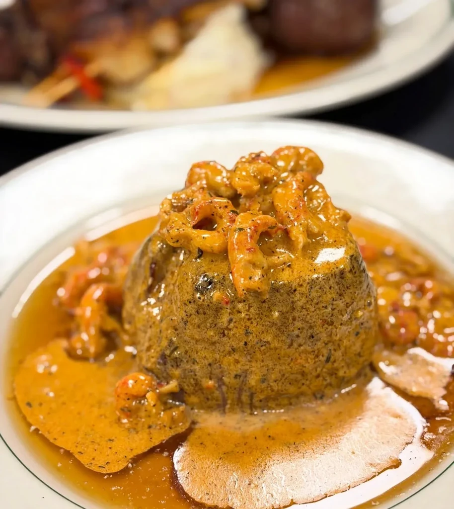 Savory grain mound with creamy crawfish sauce on a white plate.