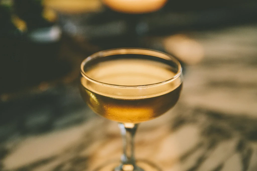 Chilled golden amber cocktail in a coupe glass, with soft lighting.