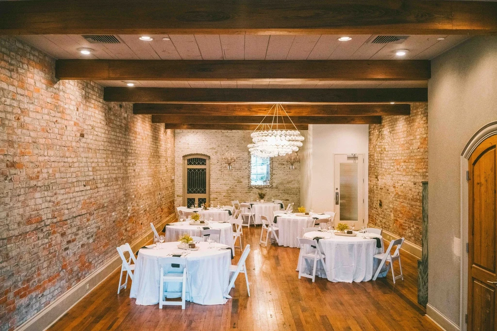 Elegant restaurant with brick walls, wood beams, spherical chandelier, set tables.