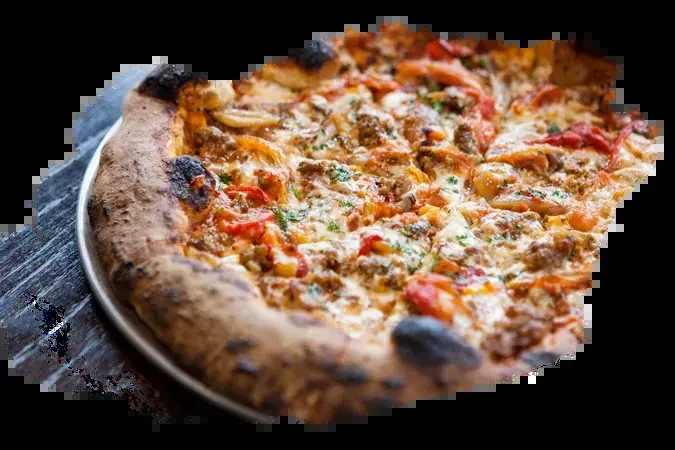 Close-up of sliced pizza with meat, vegetables, and melted white cheese.