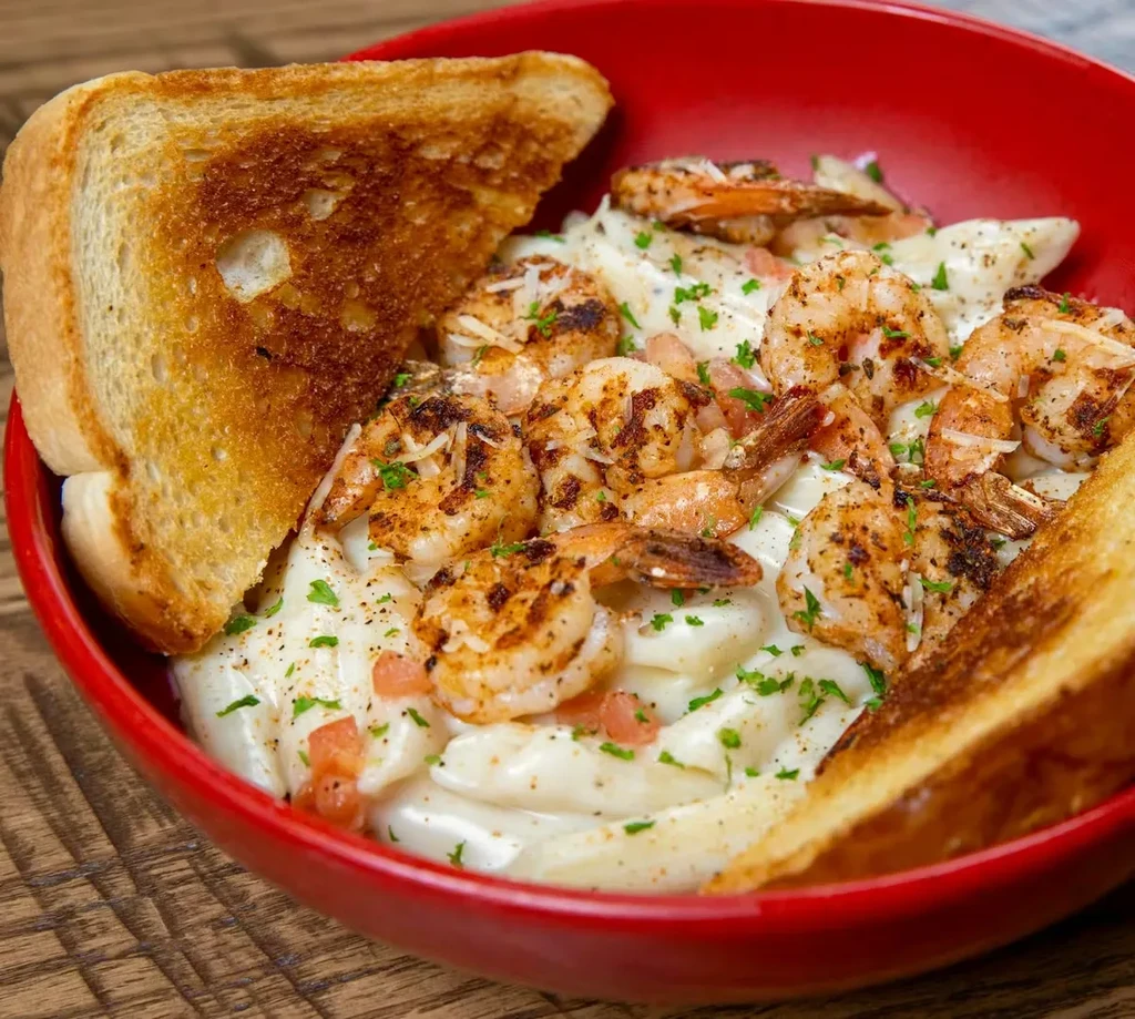 Creamy grilled shrimp pasta in red bowl with toast.