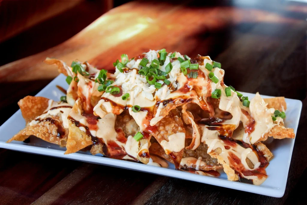 Loaded golden chips with creamy, savory sauces, cheese, and green onions.