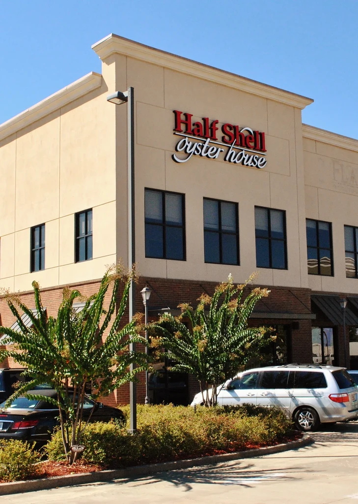 Sunlit Half Shell Oyster House building with clear blue sky and landscaping.