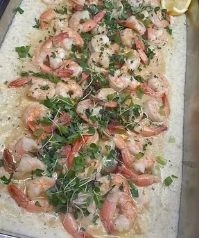 Close-up of shrimp and creamy grits or polenta with herbs and lemon.