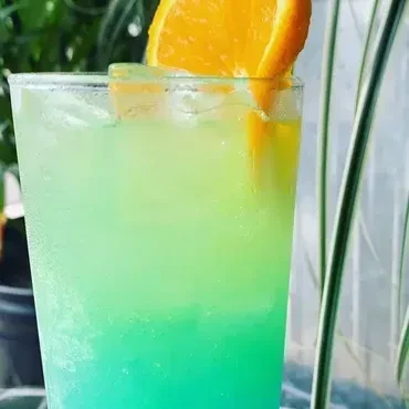 Layered blue, green, yellow drink with ice and orange slice.