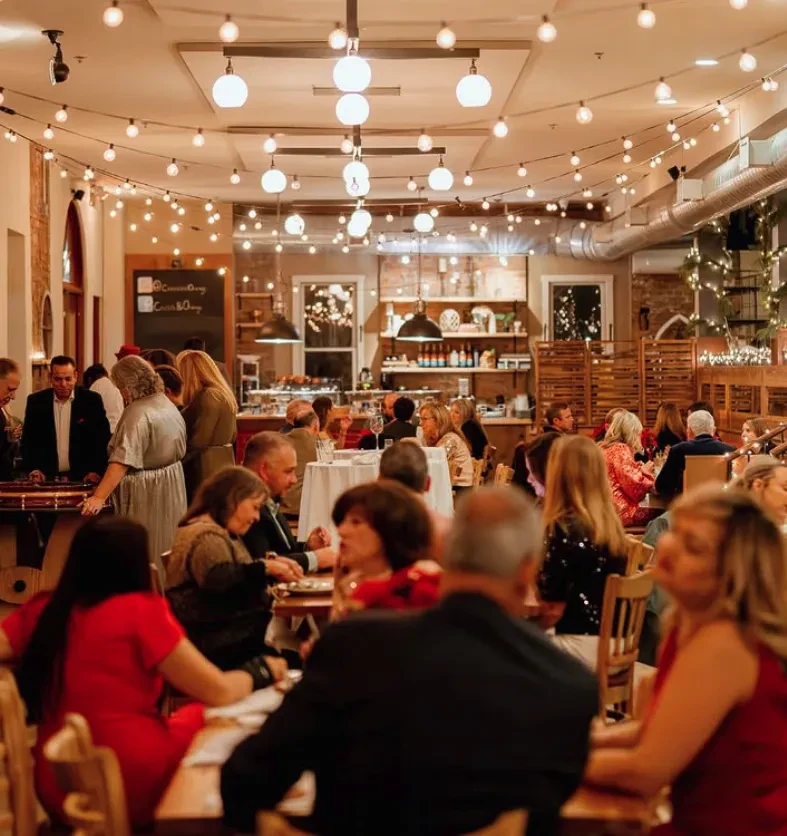 Bustling, warmly lit restaurant interior with many people and rustic decor.