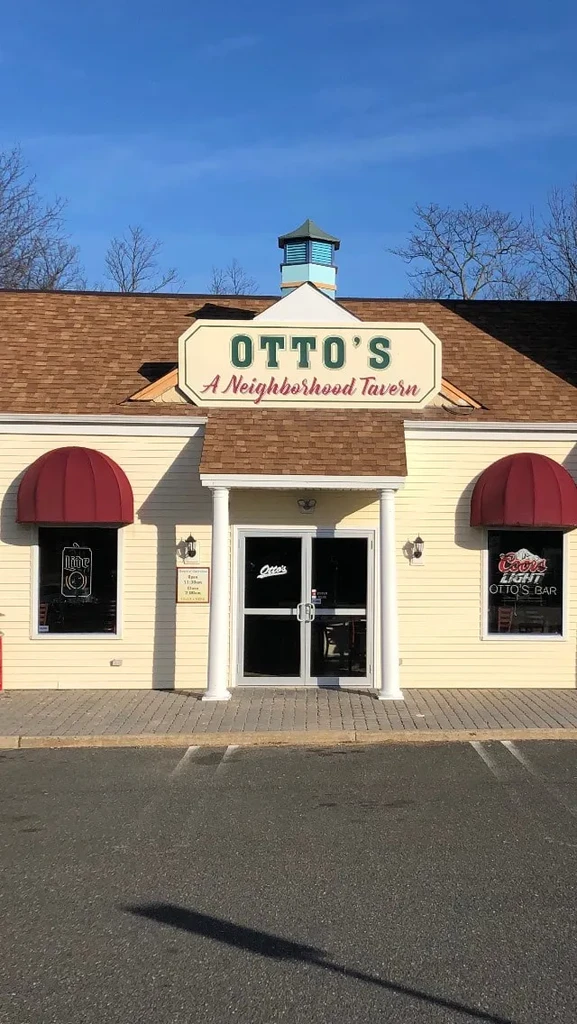 Light yellow Otto's Tavern with red awnings, prominent sign, and cupola.