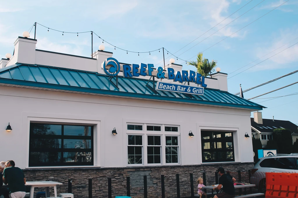 White and turquoise modern beach bar exterior with outdoor dining.