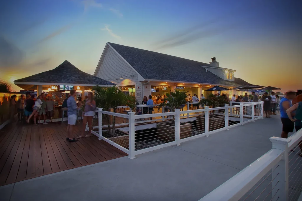 People socialize at an outdoor restaurant and bar deck at sunset.
