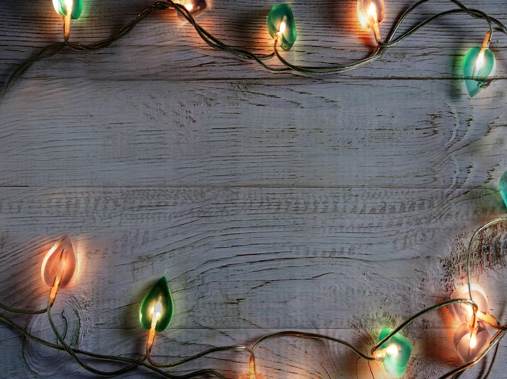 Leaf-shaped orange and teal lights frame a rustic wooden surface.