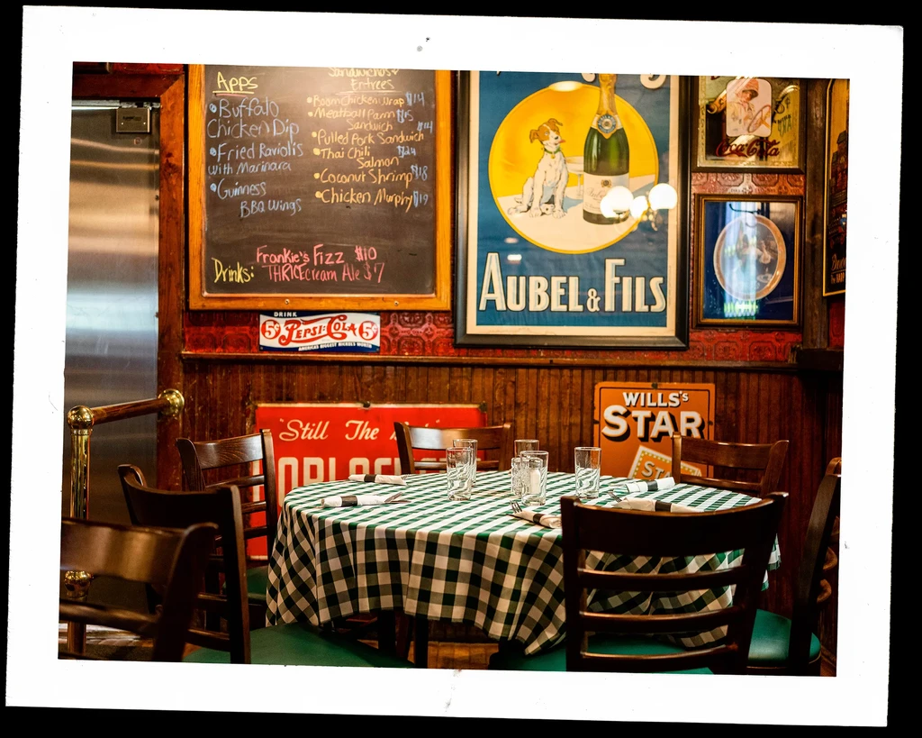 Vintage restaurant interior with checkered table, chalkboard menu, and retro signs.