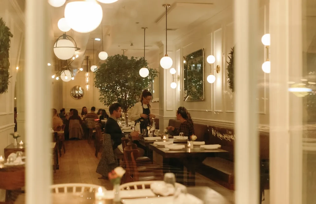 Warmly lit, elegant restaurant interior with diners and a server.