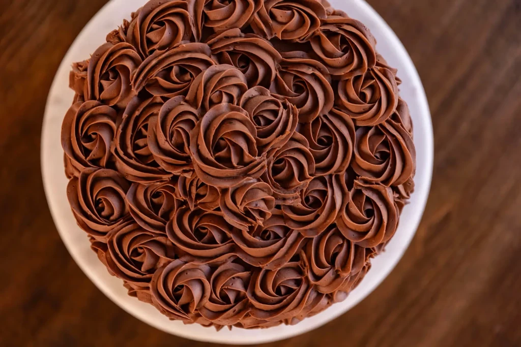 Round chocolate cake with intricate chocolate rosette frosting, top-down view.