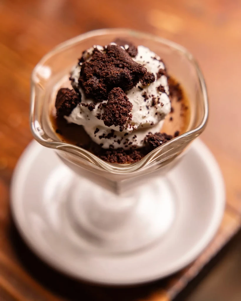Creamy dessert with whipped cream and chocolate crumbs in a glass.