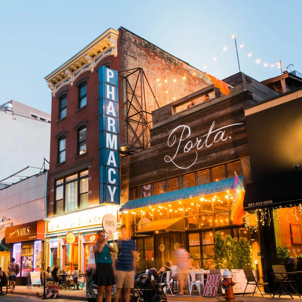 Porta restaurant's illuminated wooden facade on a lively city street at dusk.