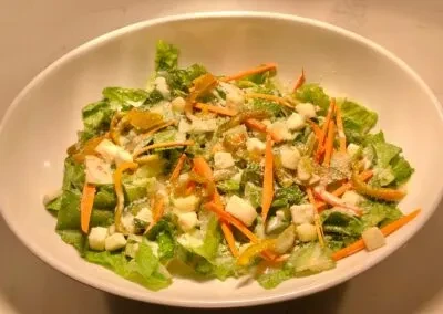 Overhead view of a salad with lettuce, carrots, and creamy dressing.