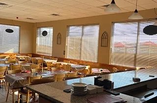 Empty casual dining restaurant interior with set tables and a service counter.