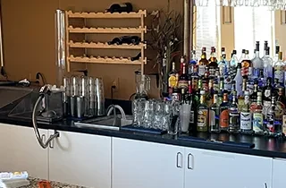 Well-stocked bar counter with liquor bottles, bar tools, and a wine rack.