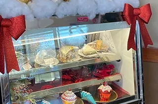 Brightly lit refrigerated dessert case filled with festive holiday treats.
