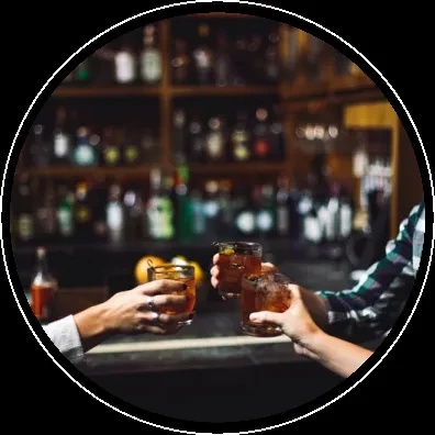Three diverse hands clinking garnished cocktails in a dim bar.