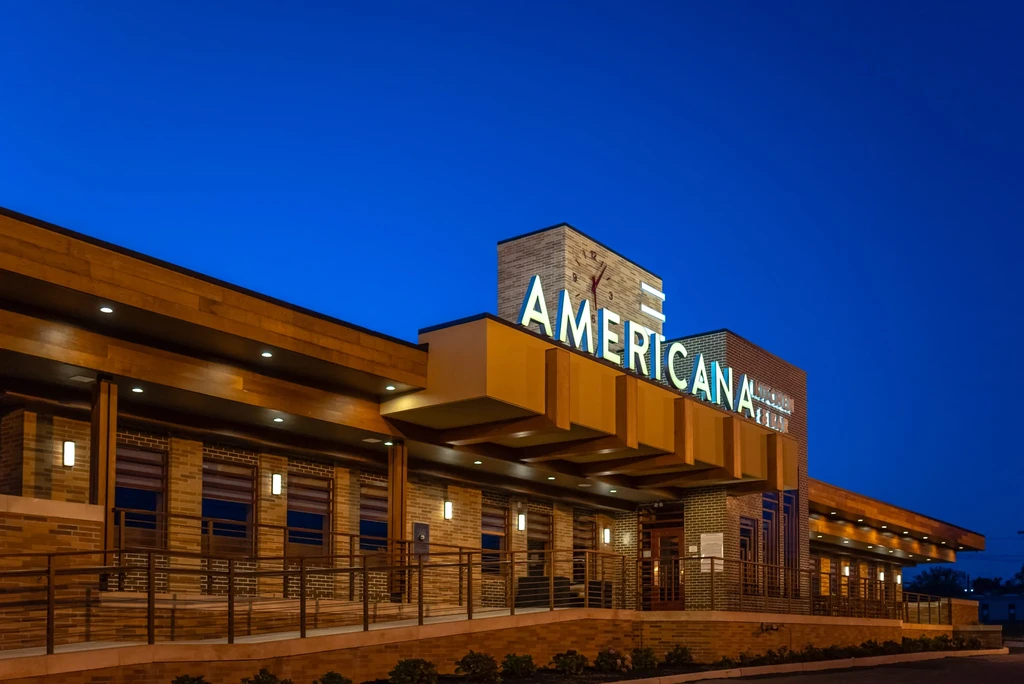 Modern Americana Kitchen & Bar exterior at twilight, with clock.