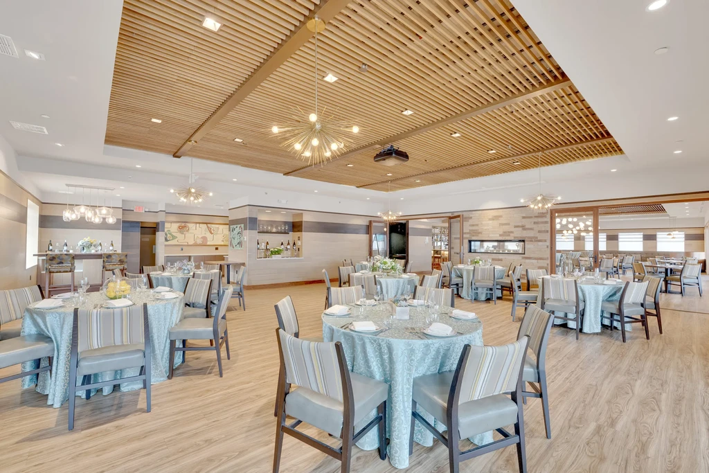 Modern restaurant interior with set tables, Sputnik chandeliers, and a fireplace.