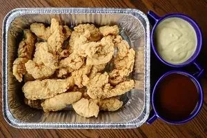 Fried chicken tenders in catering tray with two dipping sauces.