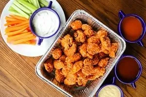 Overhead takeout spread: breaded chicken, vegetables, and various dips on wood.