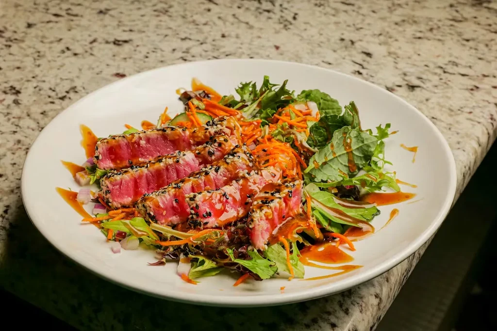 Sesame-crusted seared tuna slices with green salad and dressing.