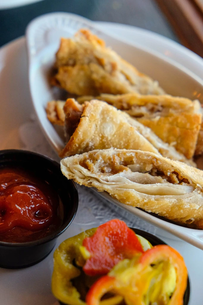 Crispy golden pastries with savory filling, red dip, and bell peppers.