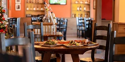 Restaurant interior showing wooden table with food, bar, and Christmas tree.
